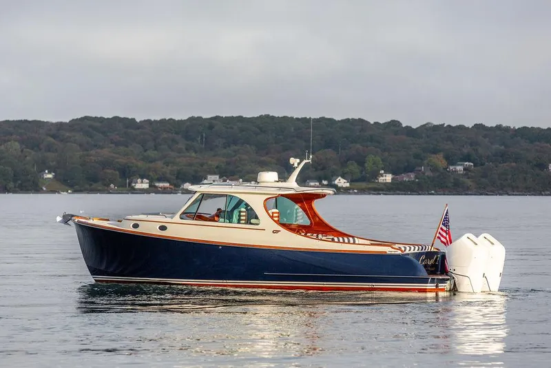 Slide: The Image of 2024 Hinckley 35 boat cruising on a calm lake with scenic forest backdrop. - 7