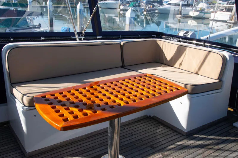 Slide: The Image of Grand Banks 42 Classic 2000 yacht with cushioned seating and wooden table on deck. - 23