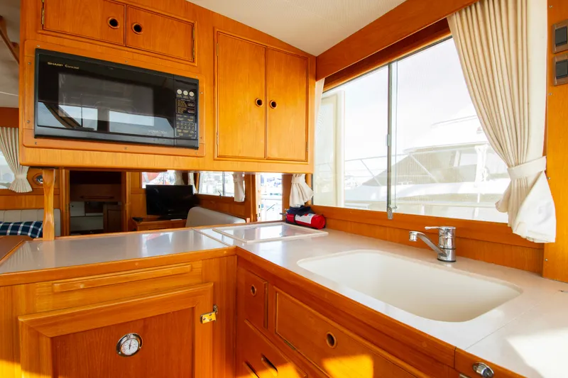 Slide: The Image of Interior of 2000 Grand Banks 42 Classic yacht, featuring a wooden kitchen with a sink and microwave. - 35
