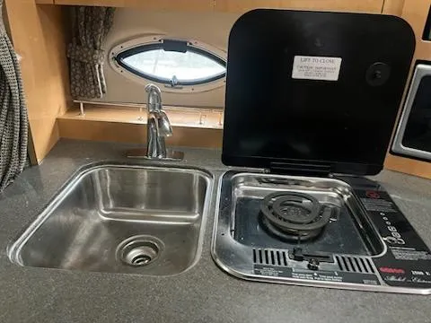 Slide: The Image of 2004 Maxum 3100 SE boat kitchen with sink and stove, featuring a compact design. - 11