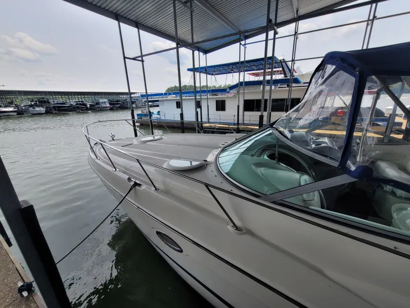 Slide: The Image of 2004 Maxum 3100 SE boat docked in a marina under a covered structure. - 2