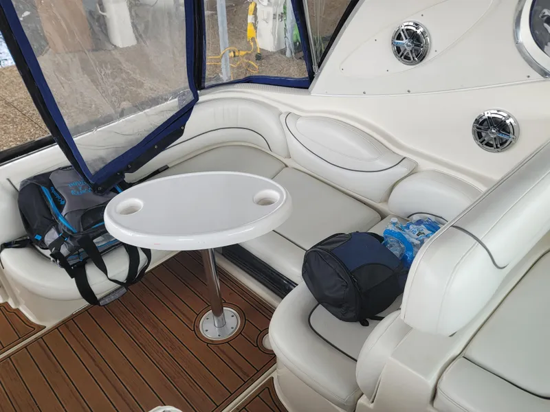 Slide: The Image of 2004 Maxum 3100 SE boat interior with seating, table, and bags on wooden deck. - 20