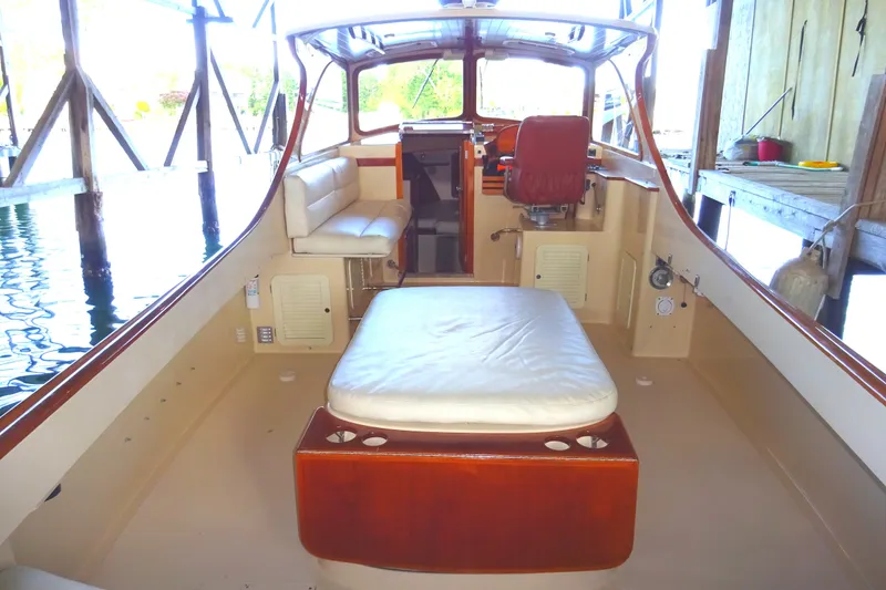 Slide: The Image of 1995 Hinckley Picnic Boat Classic interior with seating and helm, docked in a boathouse. - 17