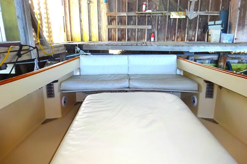 Slide: The Image of 1995 Hinckley Picnic Boat Classic interior with cushioned seating in a wooden boathouse. - 20