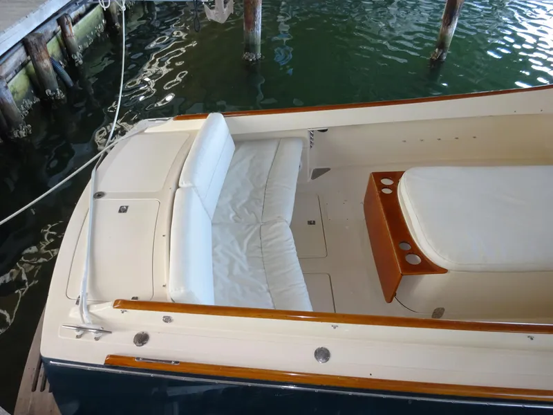 Slide: The Image of 1995 Hinckley Picnic Boat Classic with white seating, docked in calm waters. - 22