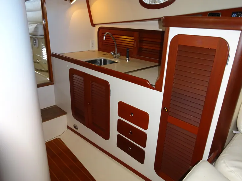 Slide: The Image of 1995 Hinckley Picnic Boat Classic interior with wooden cabinetry and compact kitchen area. - 28