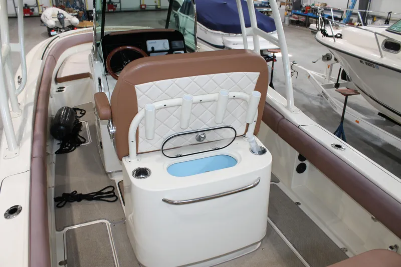 Slide: The Image of 2018 Chris-Craft Catalina 26 interior with brown seating and modern dashboard in a showroom. - 11
