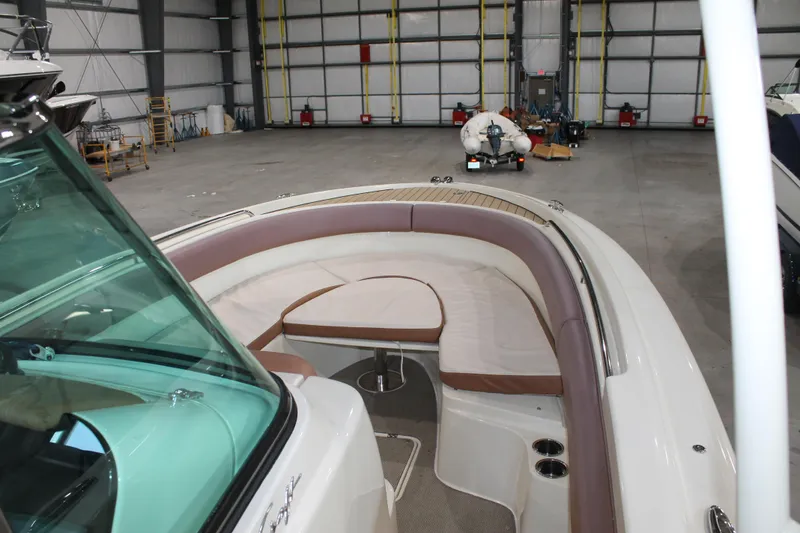 Slide: The Image of 2018 Chris-Craft Catalina 26 boat interior with cushioned seating in a spacious warehouse. - 23