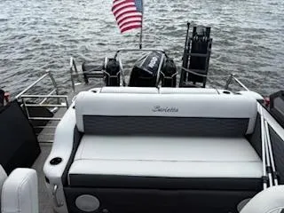 Slide: The Image of 2023 Barletta Corsa 23 UCA pontoon boat with American flag on water. - 4