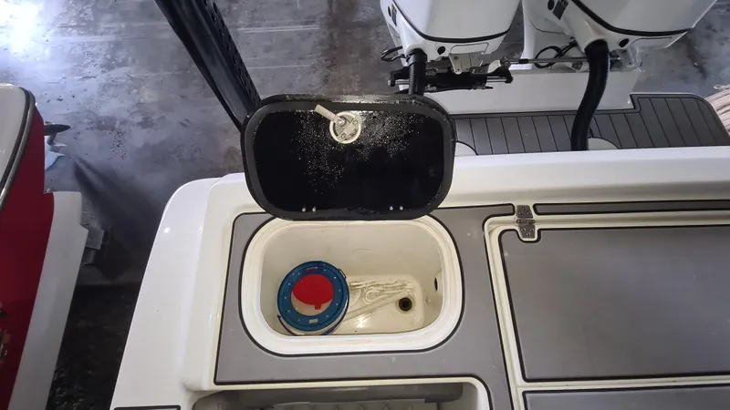 Slide: The Image of 2021 Clearwater 2800 CC boat deck with open storage compartment and visible engine controls. - 25