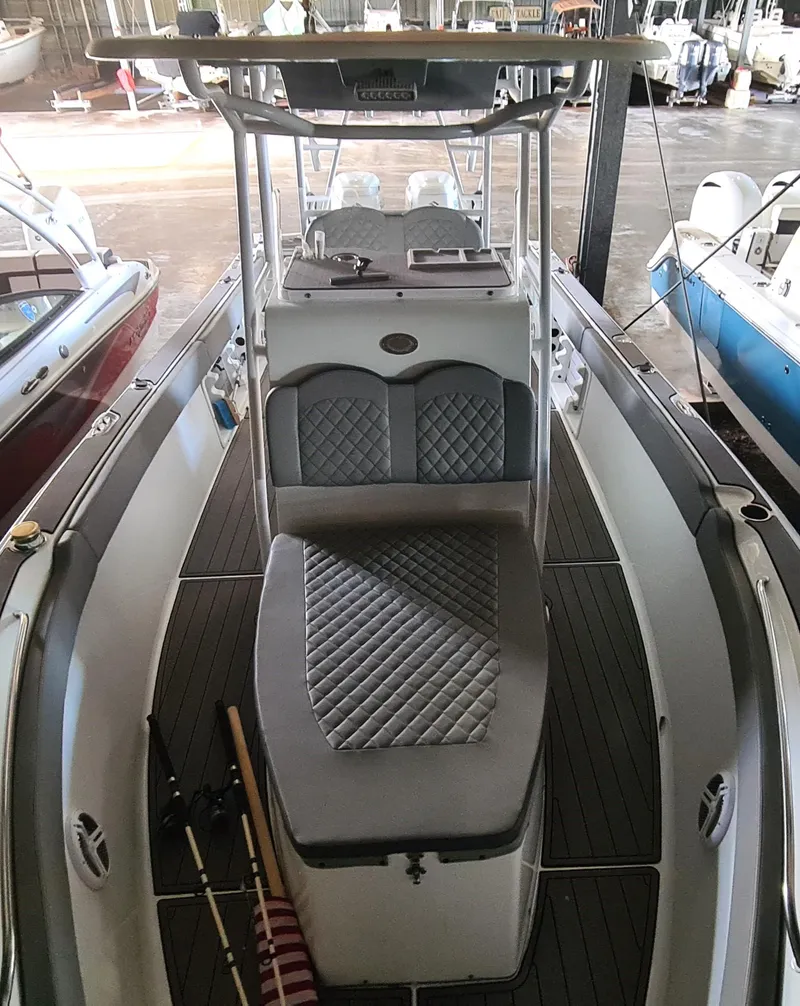 Slide: The Image of 2021 Clearwater 2800 CC boat with cushioned seating and sleek design in a marina setting. - 9