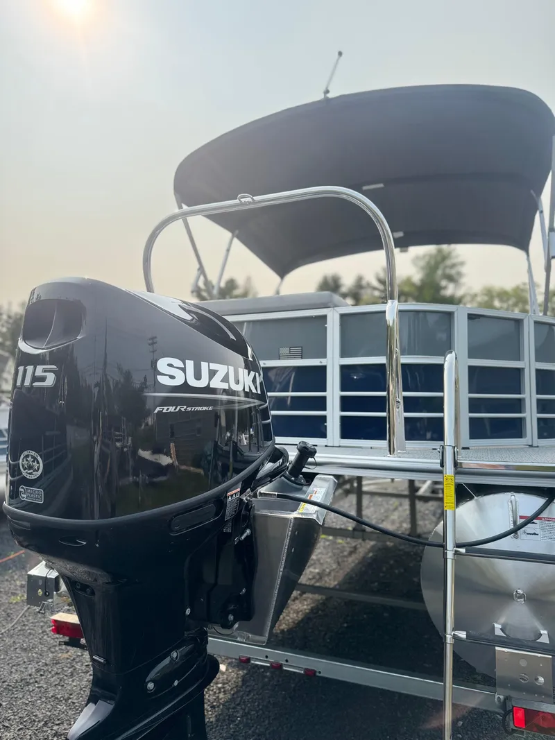 Slide: The Image of 2025 Berkshire 22CL CTS pontoon boat with Suzuki 115 outboard motor, parked outdoors. - 2
