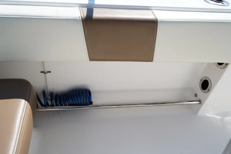 Slide: The Image of 2017 Robalo R200ES boat interior with storage compartment and coiled blue hose. - 10