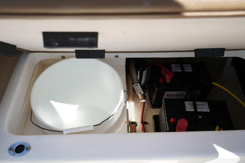 Slide: The Image of 2017 Robalo R200ES boat storage compartment with battery and bucket. - 8