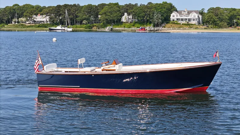 Slide: The Image of 1989 Boca Grande 26 boat on calm water, with scenic shoreline and houses in the background. - 1