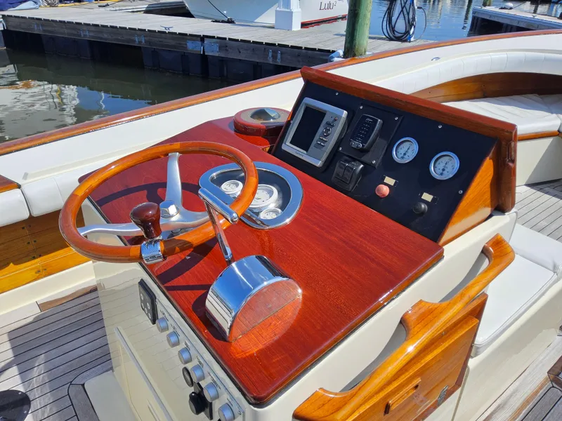 Slide: The Image of 1989 Boca Grande 26 boat helm with wooden dashboard, steering wheel, and gauges at marina. - 12