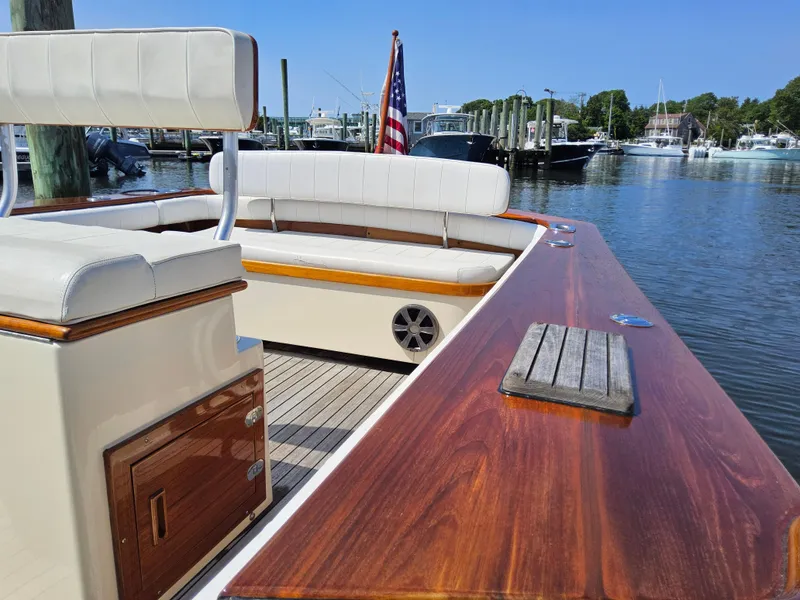 Slide: The Image of 1989 Boca Grande 26 boat with wooden deck, white seating, and American flag in marina. - 21