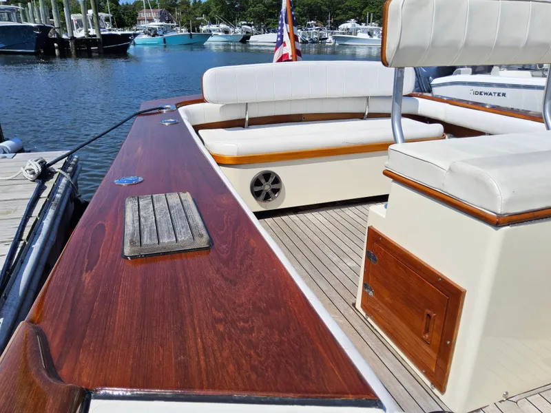 Slide: The Image of 1989 Boca Grande 26 boat with wooden deck and white seating, docked at a marina. - 22