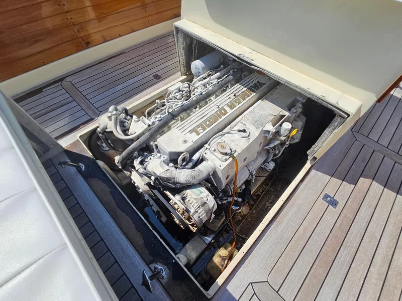 Slide: The Image of 1989 Boca Grande 26 boat engine compartment with visible engine components and wooden deck. - 29