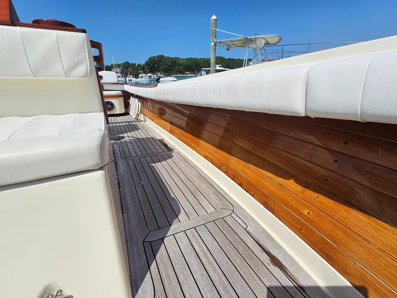 Slide: The Image of 1989 Boca Grande 26 boat interior with wooden and cushioned seating, docked under clear blue sky. - 30