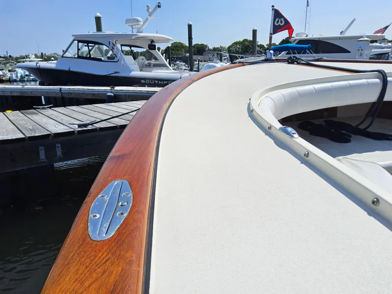 Slide: The Image of 1989 Boca Grande 26 boat with wooden trim docked at marina, clear sky background. - 31