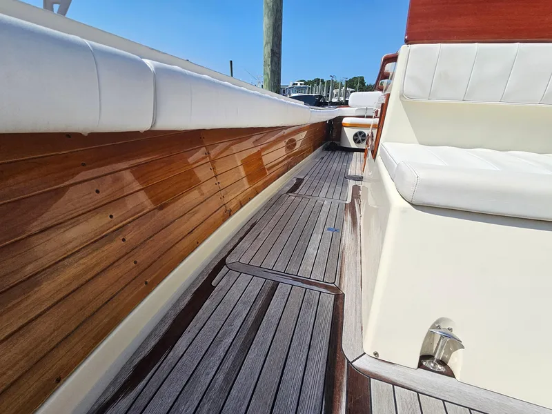 Slide: The Image of 1989 Boca Grande 26 boat with wooden deck and white seating, docked under clear blue sky. - 32