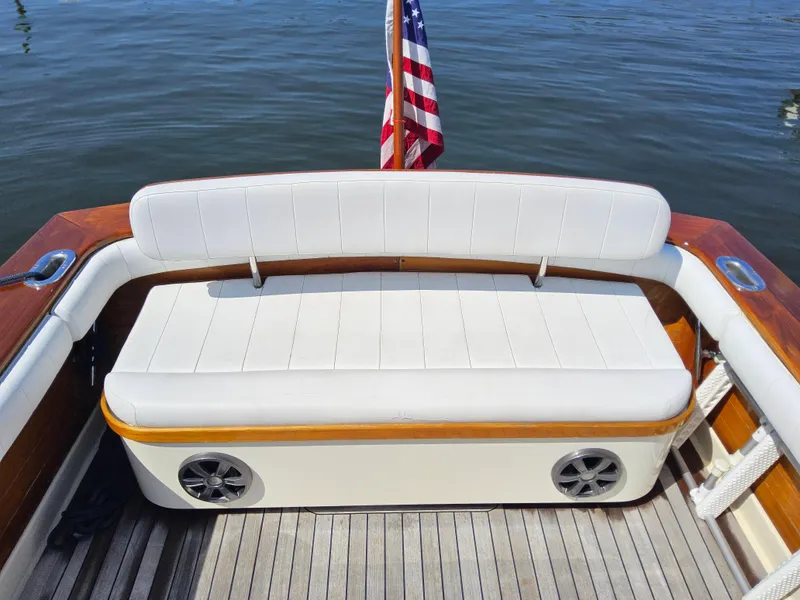 Slide: The Image of 1989 Boca Grande 26 boat with white cushioned seating and American flag on calm water. - 6