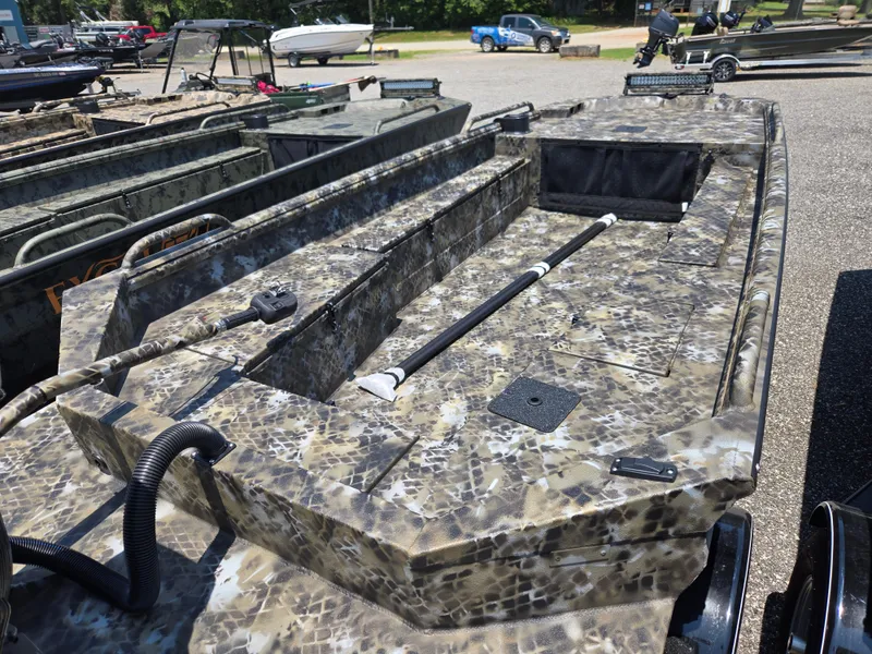Slide: The Image of 2025 Excel 1754 F4 Shallow Water boat with camouflage design, parked outdoors. - 17