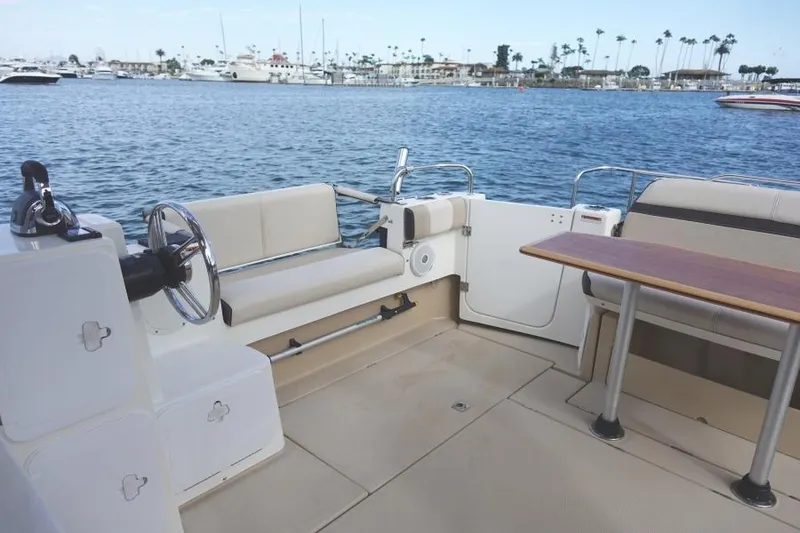 Slide: The Image of 2015 Cutwater 30 Sedan LE boat interior with seating and table, docked by the water. - 11