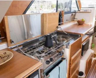 Slide: The Image of 2015 Cutwater 30 Sedan LE yacht kitchen with stove, sink, and wooden cabinetry. - 16