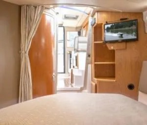 Slide: The Image of Interior of 2015 Cutwater 30 Sedan LE, featuring cozy cabin with TV and wooden accents. - 18
