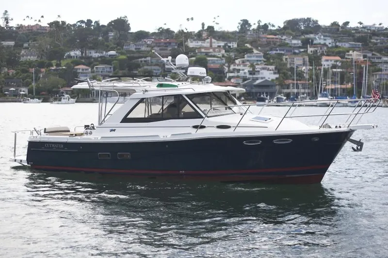 Slide: The Image of 2015 Cutwater 30 Sedan LE boat on calm water with scenic coastal background. - 4