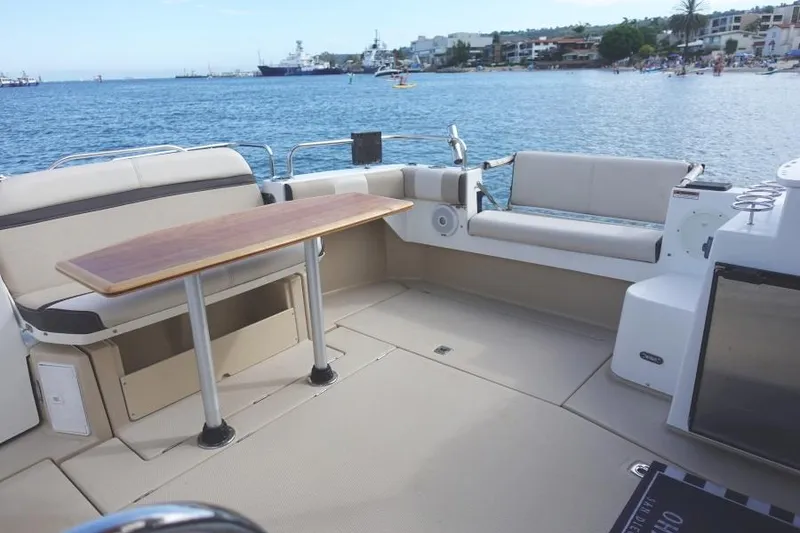 Slide: The Image of 2015 Cutwater 30 Sedan LE boat interior with seating and table, overlooking a scenic waterfront. - 9