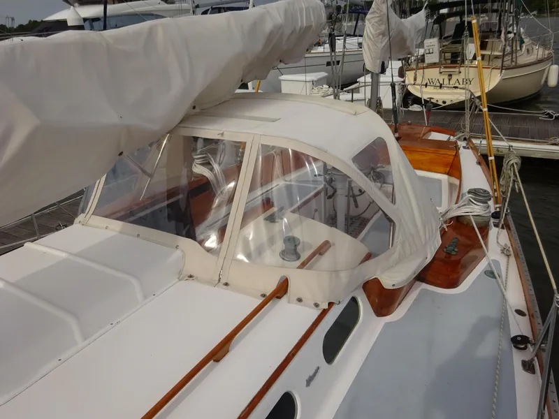 Slide: The Image of 1964 Hinckley Bermuda 40 Custom sailboat with covered cockpit and wooden accents at a marina. - 23