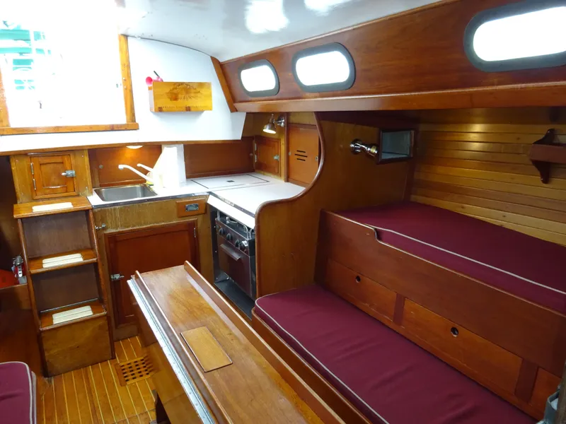 Slide: The Image of Interior of 1964 Hinckley Bermuda 40 Custom yacht with wooden cabinetry and maroon seating. - 34