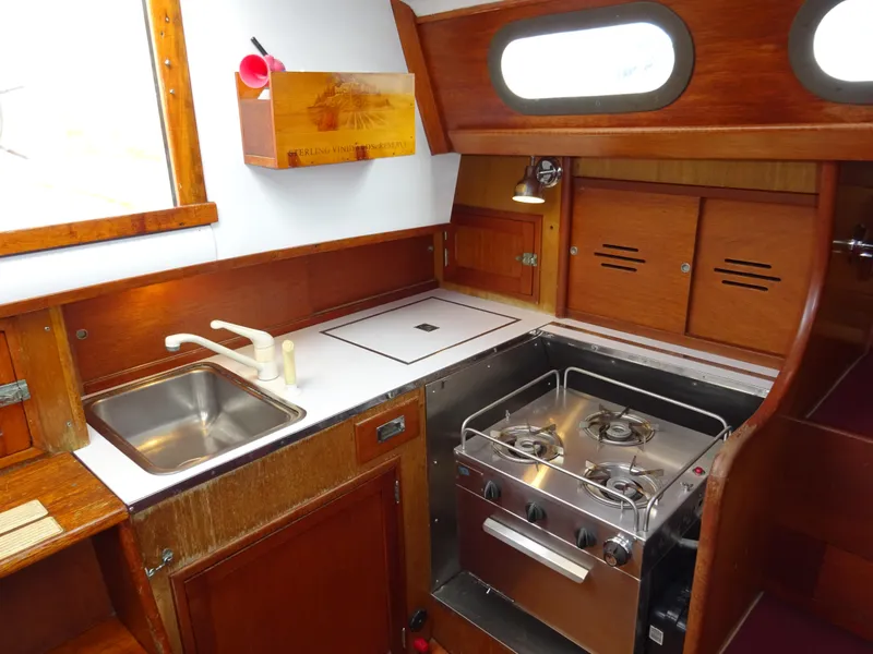 Slide: The Image of 1964 Hinckley Bermuda 40 Custom yacht kitchen with stove, sink, and wooden cabinetry. - 40