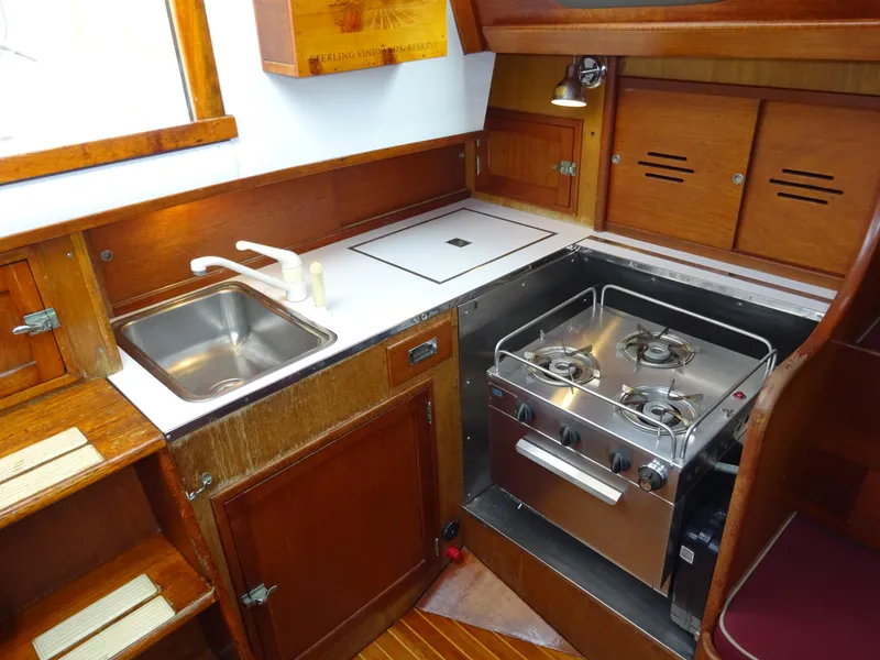Slide: The Image of 1964 Hinckley Bermuda 40 Custom yacht kitchen with stove, sink, and wooden cabinetry. - 42