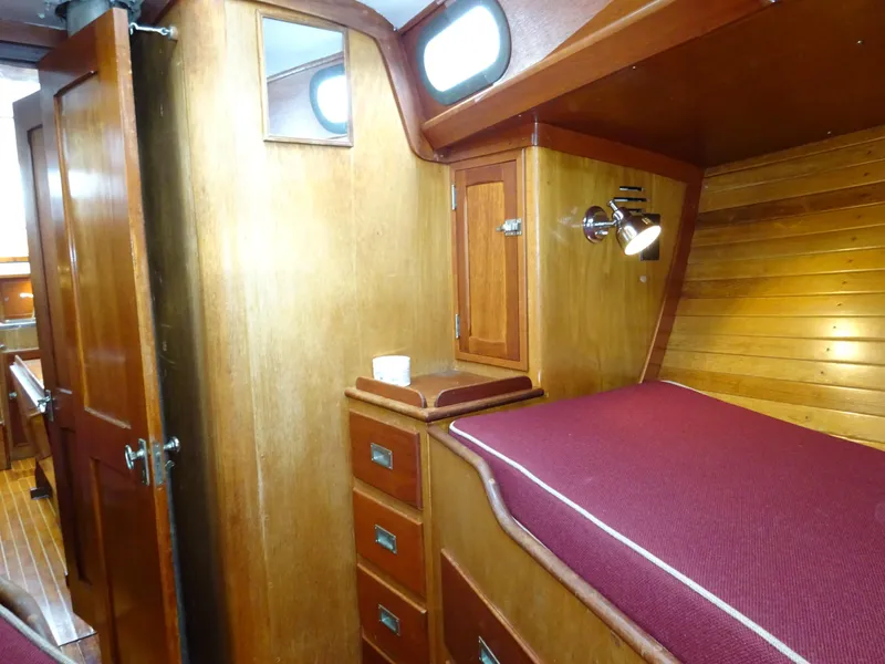 Slide: The Image of Interior of 1964 Hinckley Bermuda 40 Custom yacht with wooden cabinetry and maroon bedding. - 44