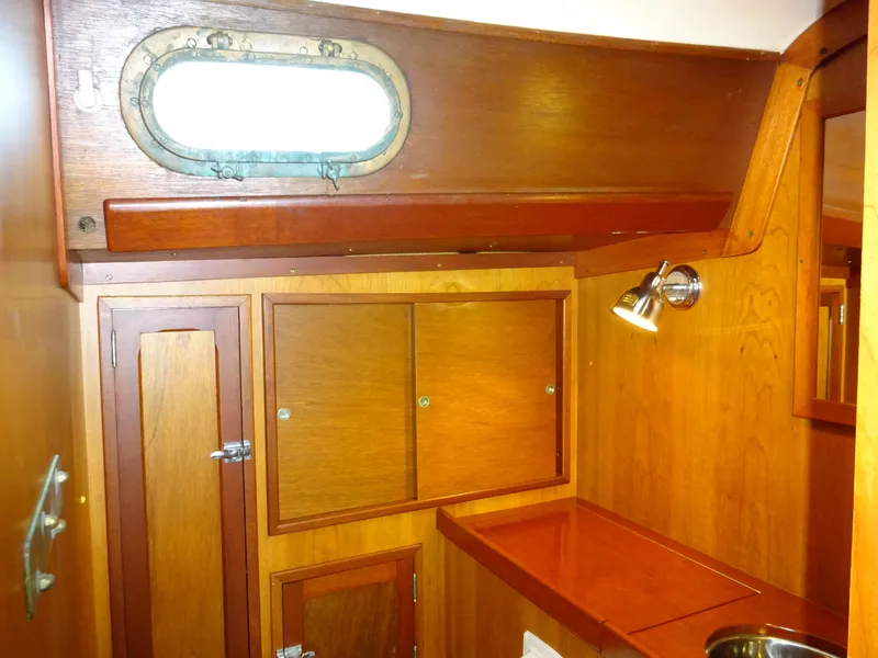 Slide: The Image of Hinckley Bermuda 40 Custom 1964 interior with wooden cabinetry and porthole window. - 48