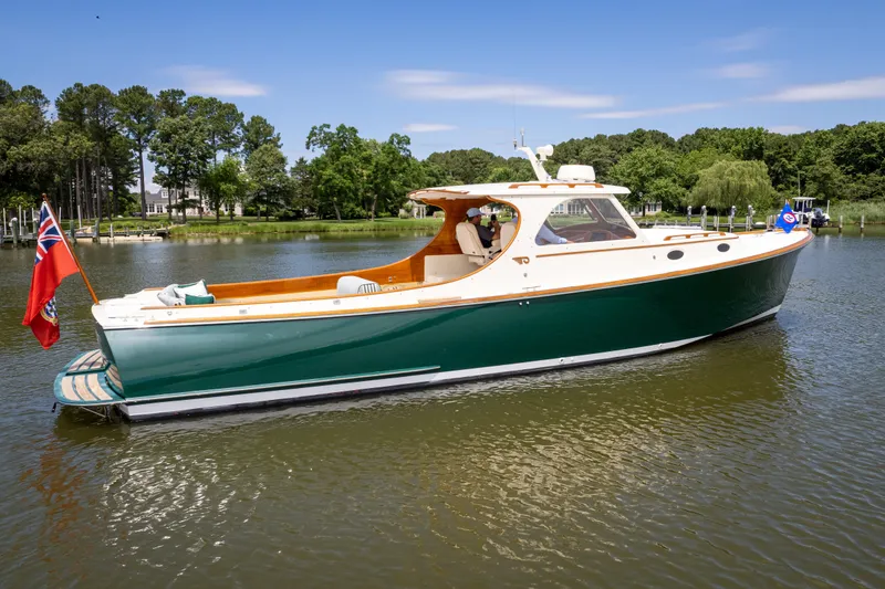 Slide: The Image of 1997 Hinckley Picnic Boat Classic on a serene lake with lush green surroundings. - 10