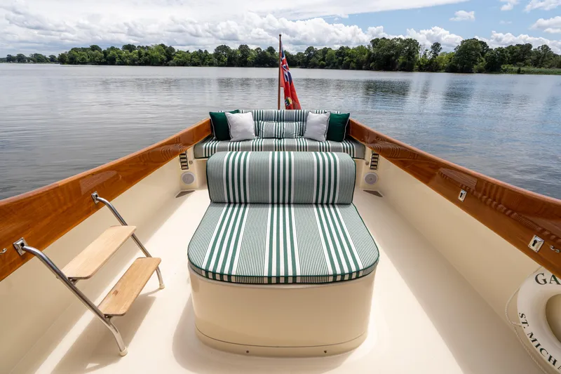 Slide: The Image of 1997 Hinckley Picnic Boat Classic with striped seating on a serene lake. - 23