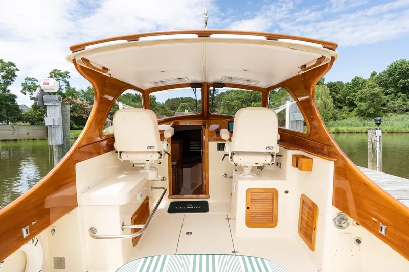 Slide: The Image of 1997 Hinckley Picnic Boat Classic interior with wooden accents and seating, docked by lush greenery. - 27