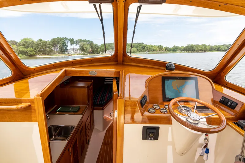 Slide: The Image of 1997 Hinckley Picnic Boat Classic interior with wooden dashboard and steering wheel, overlooking serene waters. - 31