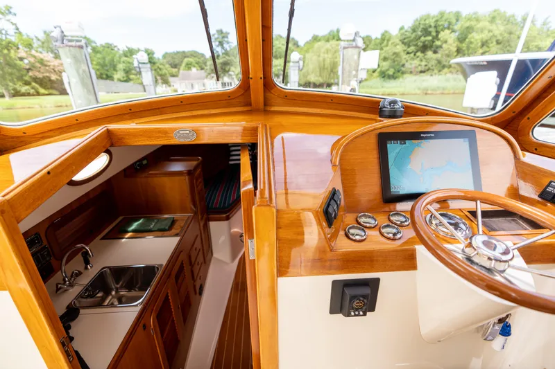 Slide: The Image of 1997 Hinckley Picnic Boat Classic interior with wooden helm, navigation screen, and compact kitchen area. - 35
