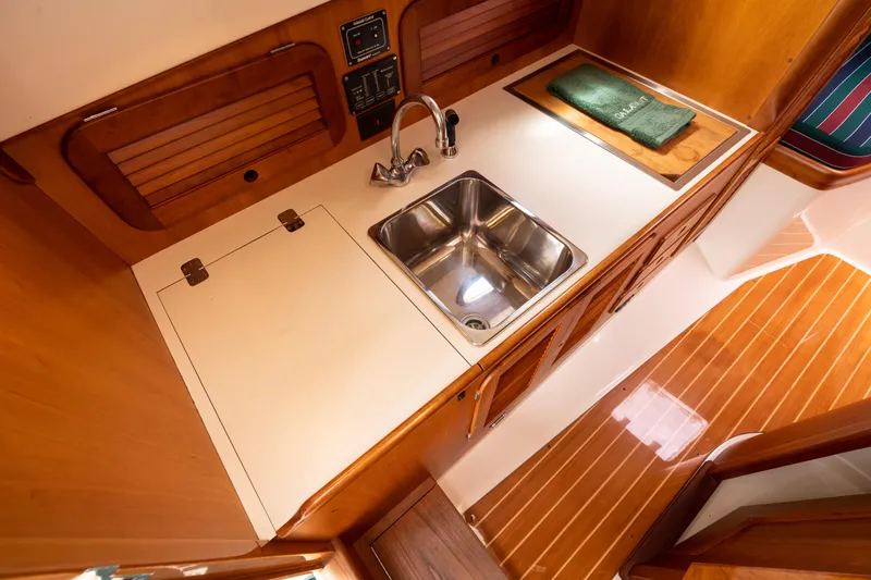 Slide: The Image of 1997 Hinckley Picnic Boat Classic galley with sink, wooden cabinetry, and countertop. - 36