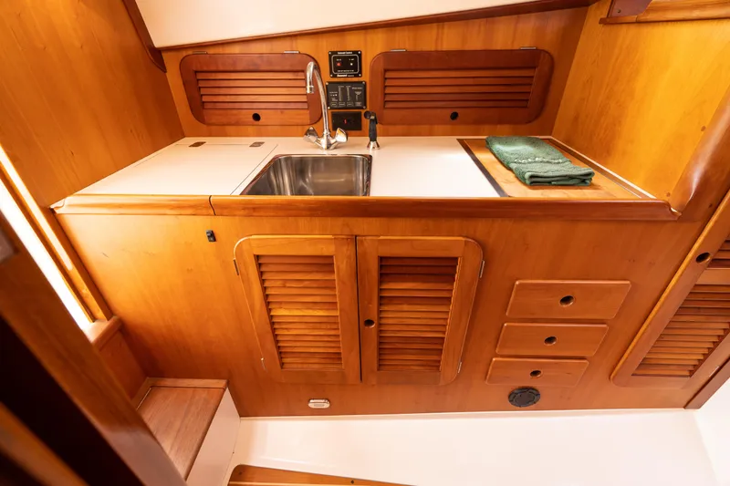 Slide: The Image of Hinckley Picnic Boat Classic 1997 interior galley with wooden cabinetry and stainless steel sink. - 37