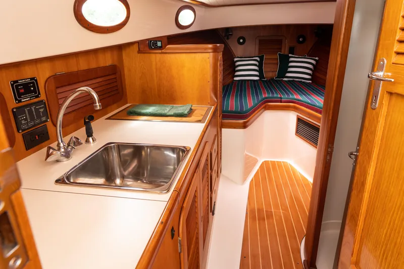 Slide: The Image of Interior of 1997 Hinckley Picnic Boat Classic with wood finish and compact kitchen area. - 38
