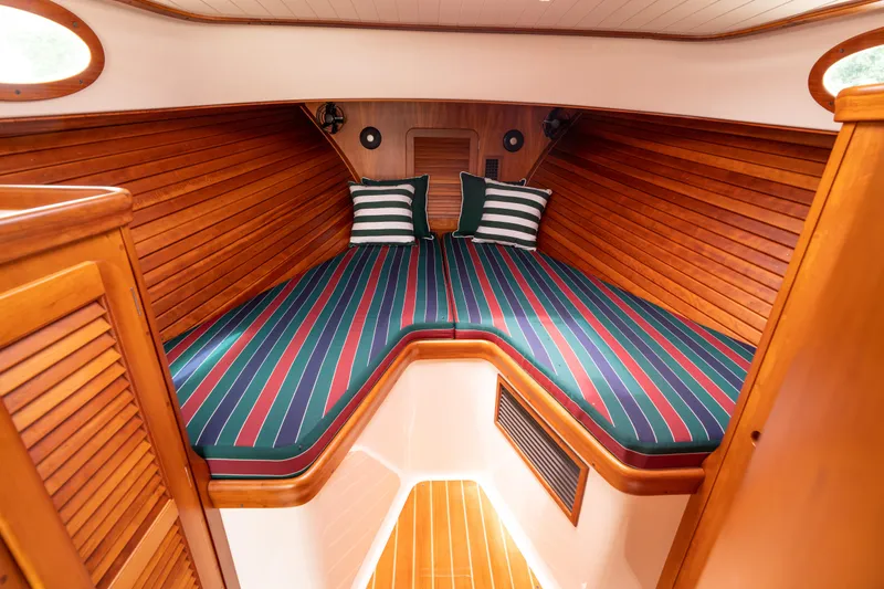 Slide: The Image of 1997 Hinckley Picnic Boat Classic cabin with striped bedding and wooden interior. - 39