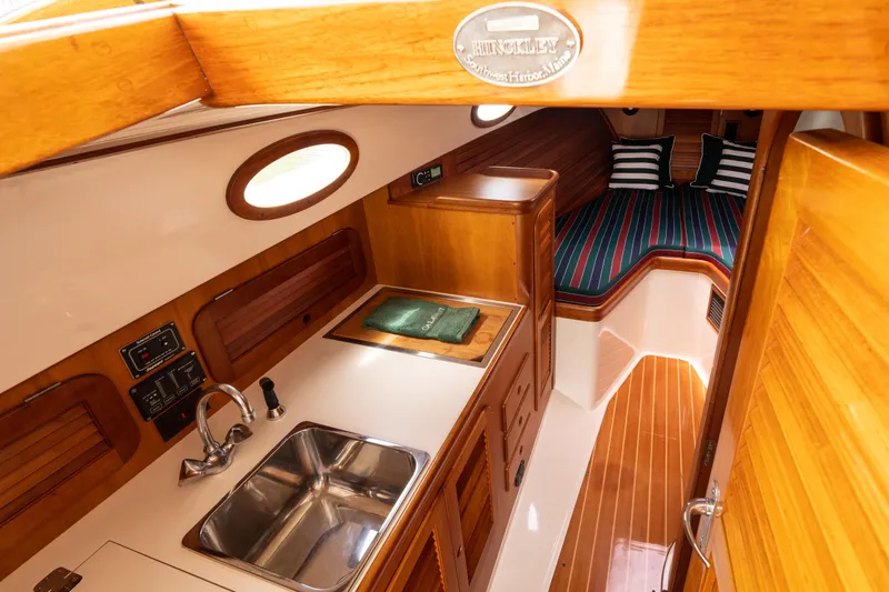 Slide: The Image of Interior of 1997 Hinckley Picnic Boat Classic, featuring wood finishes and compact kitchen area. - 4