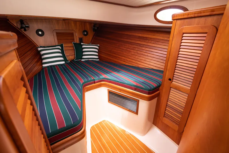 Slide: The Image of 1997 Hinckley Picnic Boat Classic cabin with striped bedding and wooden interior. - 40